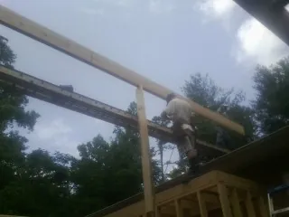 Carpenter setting a ridge beam over a new addition frame — Ice Dam Removal by Roofing Brothers in Macclenny