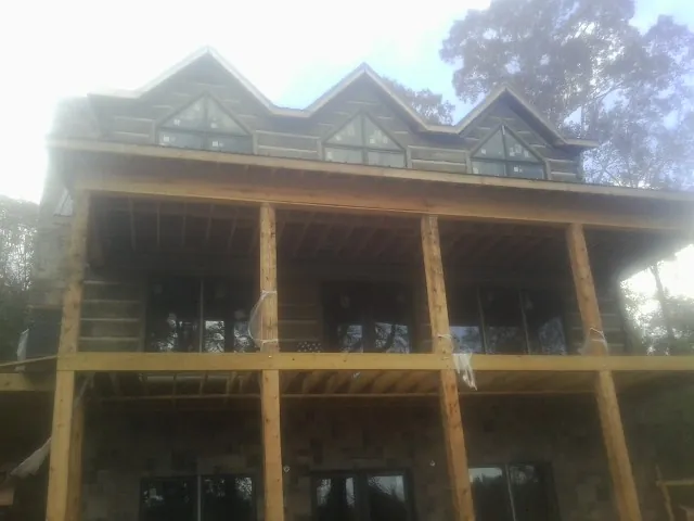 Dormers and porch framing on a large log home under construction — Roof Coating work by our crew in Macclenny