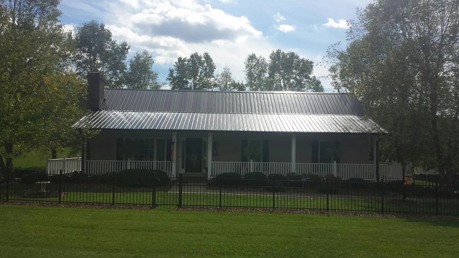 Gray metal roof on a brick ranch with a full width front porch — Gutter Guard Installation work by our crew in Macclenny