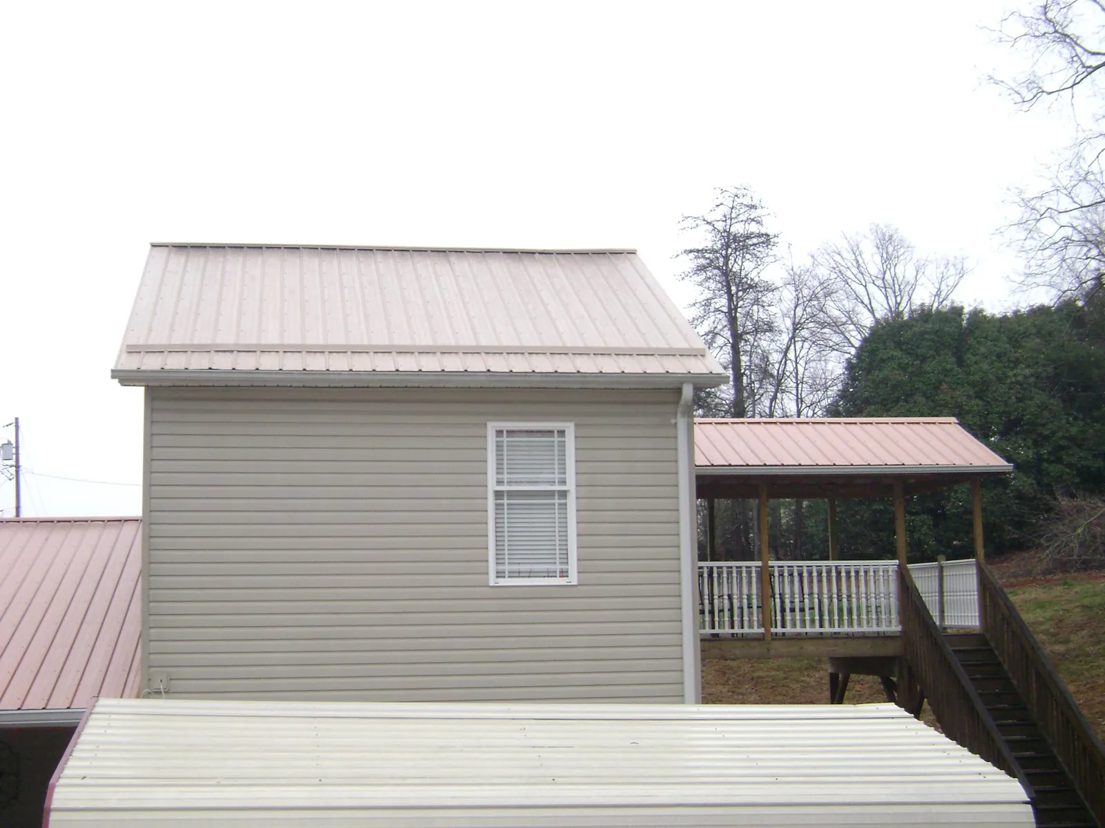 Tan metal roofs on a two story addition and attached porch, from a Roof Replacement job in Macclenny