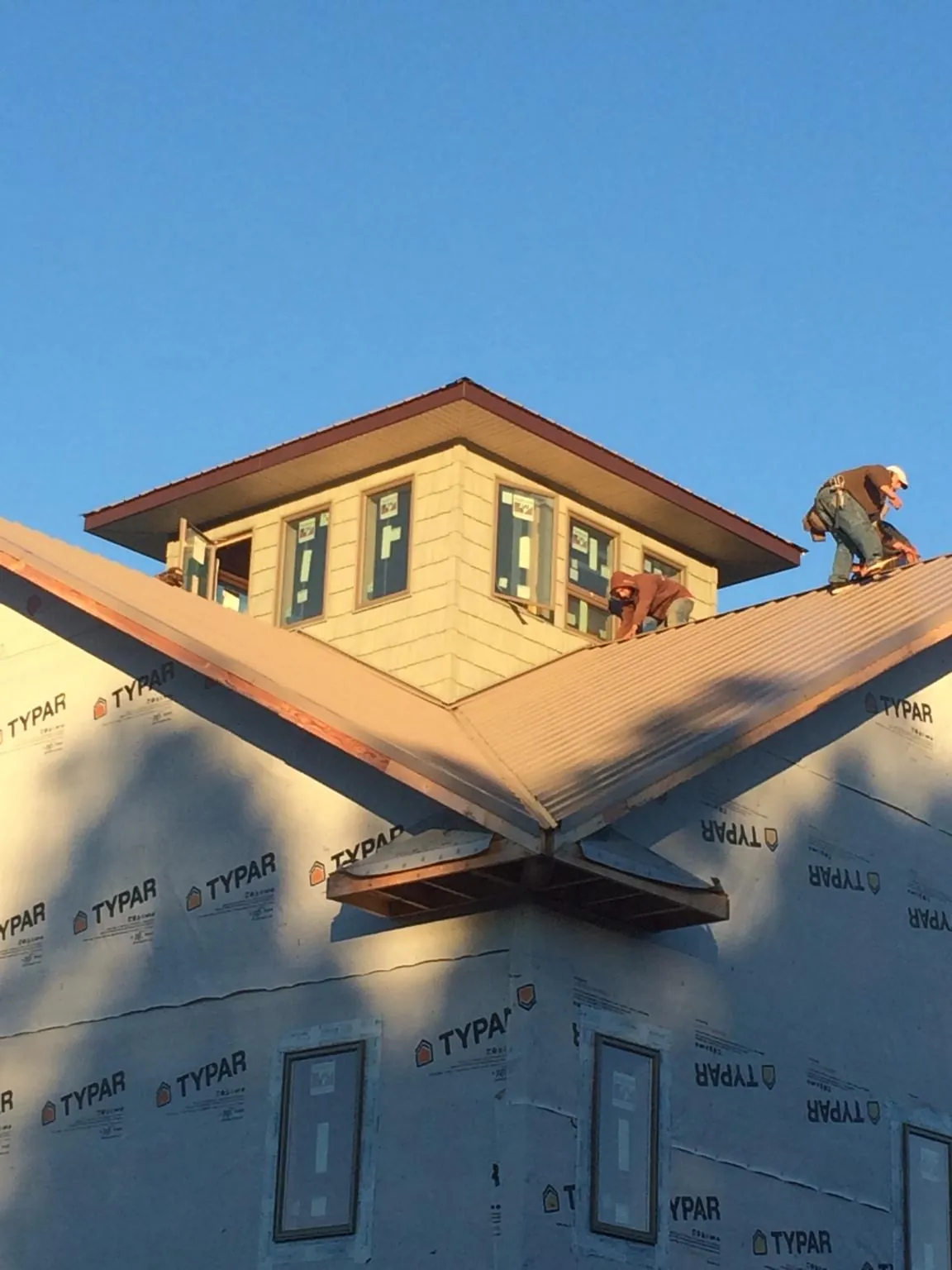 Roofers working around a rooftop cupola on a new metal roof at sunset — Roof Waterproofing in Macclenny by Roofing Brothers